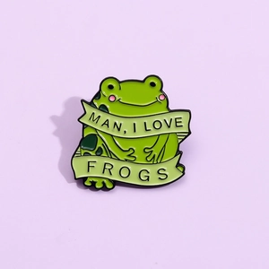 Dettaglio della spilla rana in smalto verde con testo Man I Love Frogs su viola