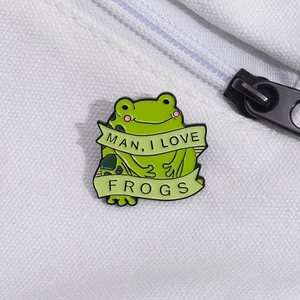 Cute green frog enamel pin badge with banner text on white canvas bag background