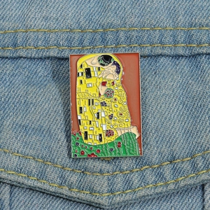 Détail de la broche en émail Le Baiser de Klimt épinglée sur une veste en jean
