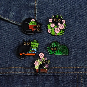 Set of five black enamel cat pins with succulent plants and pink flowers on denim
