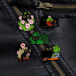 Detail of five black cat enamel pins with floral designs pinned to a black leather jacket