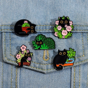 Set of 5 black cat enamel pins featuring plants and cacti pinned on a denim jacket