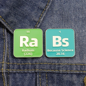 Detailed close-up of Ra and Because Science enamel pins on blue denim fabric