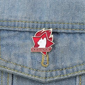 Star-shaped enamel cat pin attached to blue denim jacket pocket, close-up view