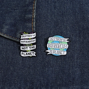 Detail van emaille pinnen met een planeet en bloemen op blauwe denim stof
