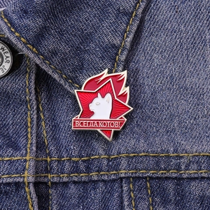 Detail of a retro Soviet style star cat enamel pin pinned on blue denim jacket fabric