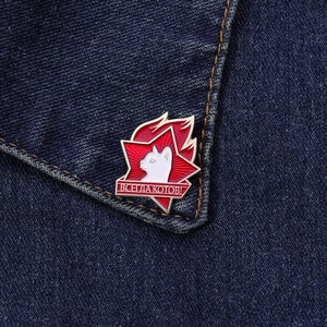 Detailed view of white cat enamel pin with red star on denim jacket collar