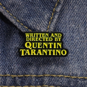 Vue macro du pin's émaillé Quentin Tarantino sur une veste en jean avec détails