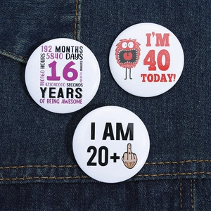 Detailed view of three creative birthday badges on denim fabric showing various ages