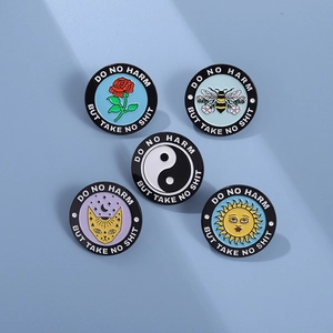 Detail of five enamel pins with floral and cat designs featuring Do No Harm slogan