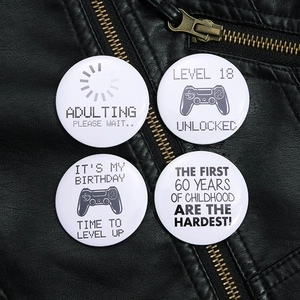 Close-up of four round gaming-themed pin-back buttons on a black leather jacket
