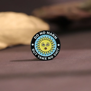 Macro detail of a round enamel pin with sun design and motivational quotes