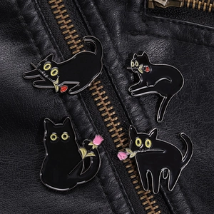 Détail de quatre épingles en émail chat noir avec roses sur une veste en cuir noir