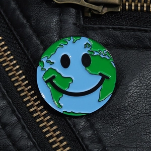 Gros plan du badge émaillé terre souriante sur le revers d'une veste en cuir noir