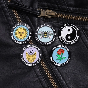 Detail of round enamel badges with rose and bee designs pinned on a black leather jacket