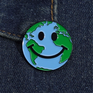 Gros plan sur le pin's émaillé Terre sourire créatif sur fond denim foncé