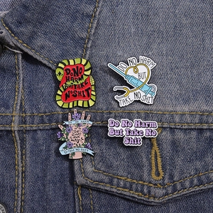 Detailed view of enamel badges featuring snake and syringe designs on denim jacket