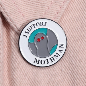 Close-up of I SUPPORT MOTHMAN enamel pin on pink fabric showing detailed zinc alloy craft