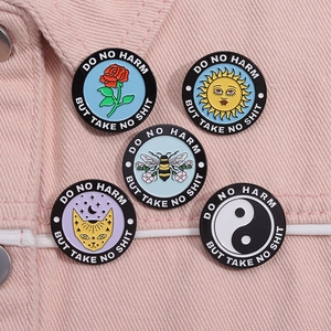 Detail of five enamel pins with slogan Do No Harm But Take No Shit on pink denim jacket