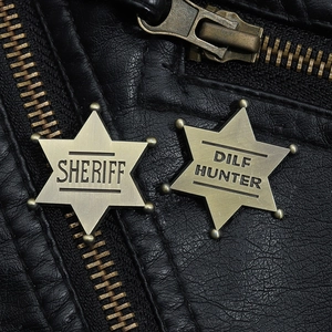 Macro shot of brass Sheriff and Dilf Hunter star badges on a black leather jacket