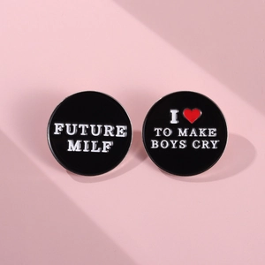 Detail of round black enamel pins with slogans Future Milf and I Love To Make Boys Cry