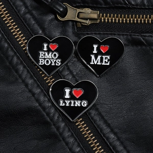 Close-up of heart-shaped enamel pins on black leather jacket featuring gothic phrases