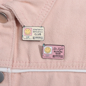 Detail of pink and beige enamel pins with club motifs on pink denim jacket texture