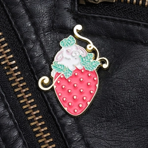 Close-up of a cute white rabbit and red strawberry enamel pin on a black leather jacket