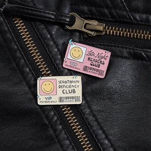 Detail of pink and white enamel square pins pinned on a black leather jacket