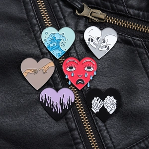 Detail view of heart-shaped enamel pin set with skull and wave patterns on leather jacket