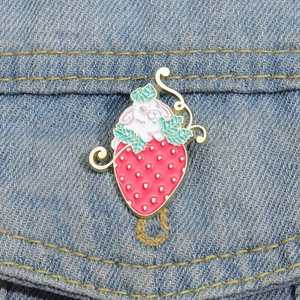 Cute strawberry rabbit enamel pin displayed on blue denim pocket with vibrant gold detailing