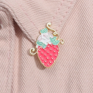 Close-up of a cute strawberry rabbit metal pin attached to light pink denim fabric