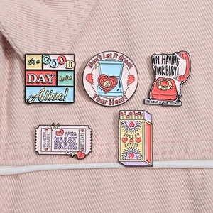 Set of five colorful enamel pins including retro phone and matchbox on pink denim fabric