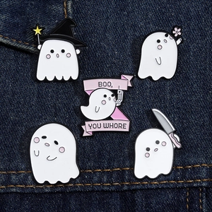 Close-up of five cute enamel ghost brooches with diverse designs on blue denim fabric