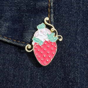 Close-up of a cute rabbit and strawberry enamel pin on dark blue denim fabric