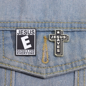 Detail of Jesus Saves cross and letter badges pinned on blue denim jacket fabric
