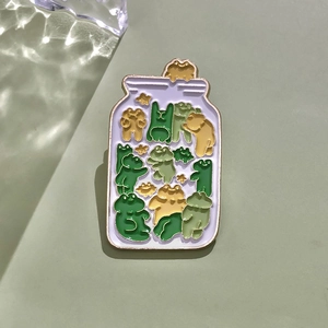 Macro shot of cute enamel frog jar pin with golden alloy edges on green background