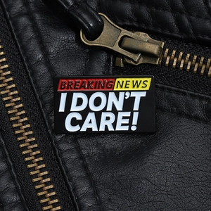 Dettaglio della spilla smaltata Breaking News I Don't Care su una giacca di pelle nera