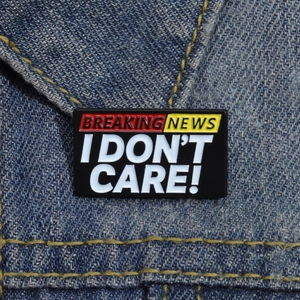 Detail der Breaking News I Don't Care Emaille-Anstecknadel an einem blauen Jeansjackenkragen