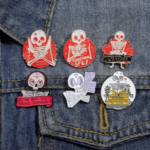 Detailed close-up of six funny skull enamel pins on denim, featuring various witty slogans