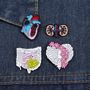 Set of four anatomical organ enamel pins including heart and ribs on blue denim fabric