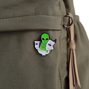 Detailed view of ET alien sitting on a toilet reading newspaper enamel pin on canvas bag