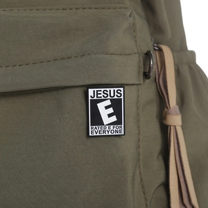 Macro shot of Jesus Rated E for Everyone enamel pin on army green canvas bag fabric