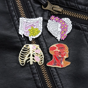 Detailed close-up of four anatomical enamel pins featuring hearts, ribs, and flowers