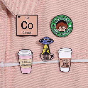 Set mit fünf Kaffee-Emaille-Pins präsentiert auf einem rosa Denim-Hintergrund
