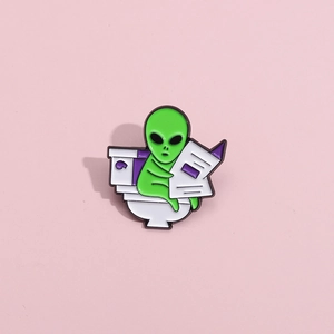Funny green alien enamel pin sitting on a toilet reading newspaper lapel badge