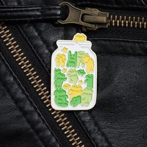 Close-up of a colorful jar of frogs enamel pin on a black leather jacket lapel