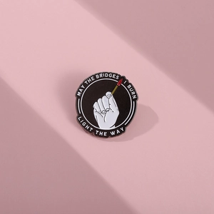 Detail of round enamel pin showing matchstick art and motivational English text