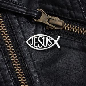Macro shot of silver Ichthys Jesus fish brooch pinned on black leather jacket texture