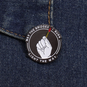 Macro detail of a round enamel pin with hand and matchstick on blue denim fabric